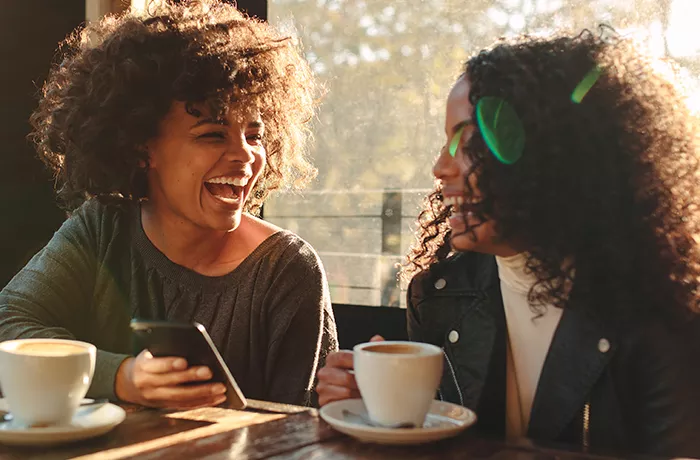 two friends having a coffee and laughing