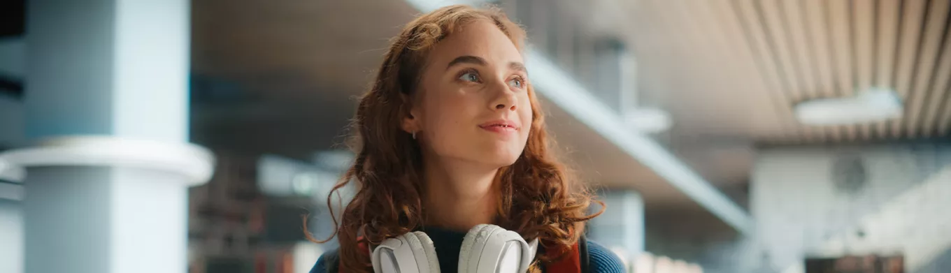 young woman looking happy with headphones around her neck